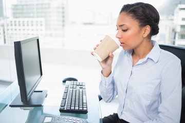 Fototapeta na wymiar Relaxed young dark haired businesswoman drinking coffee