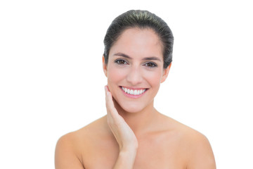 Smiling bare brunette touching her left cheek