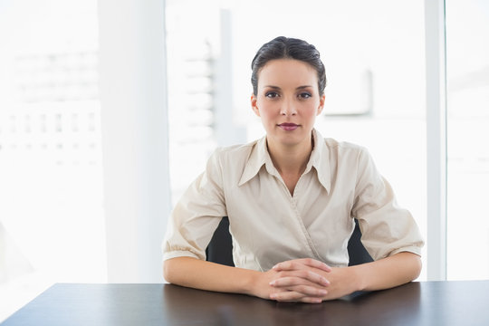 Serious stylish brunette businesswoman looking at camera and joi