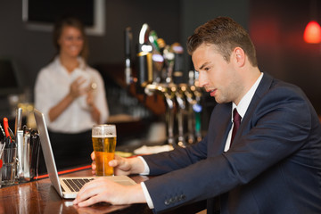 Businessman having a beer while working on his laptop