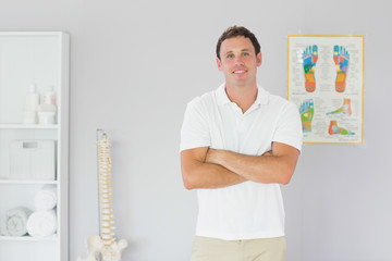 Handsome smiling physiotherapist standing with arms crossed