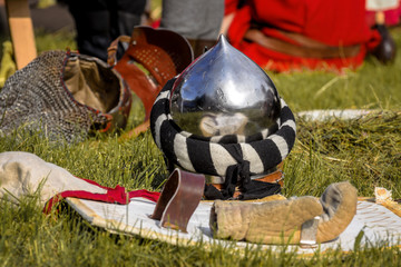 Helmet and shield of the medieval knight on the green field.
