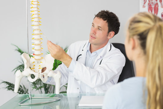 Content doctor showing a patient something on skeleton model