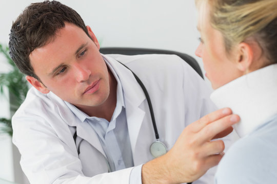 Serious doctor examining neck of a patient