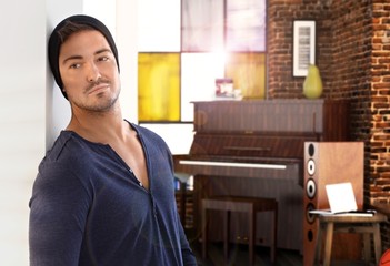 Stylish young man at home piano in background