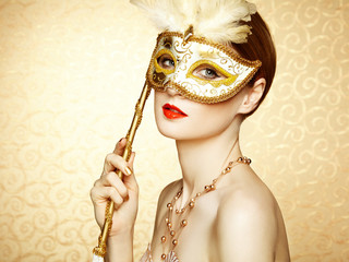 Beautiful young woman in mysterious golden Venetian mask