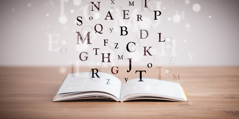 Opened book with flying letters