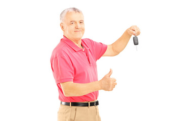 Smiling senior man holding a car key and giving thumb up