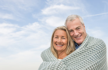 Couple Wrapped In Blanket Against Cloudy Sky