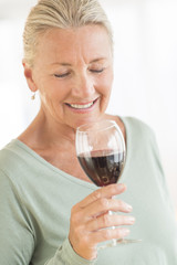 Woman Smelling Red Wine At Home