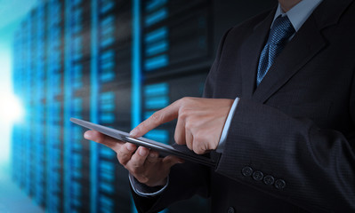 businessman hand using tablet computer and server room backgroun