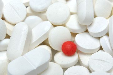 Fototapeta na wymiar red pill among white pills background