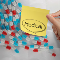 hand holding sticky note medical with Pills spilling on crumpled