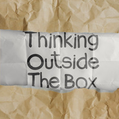 hand draws thinking outside te box on crumpled paper