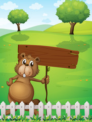 Obraz na płótnie Canvas A beaver holding an empty signboard standing near the fence