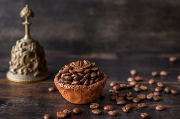 Clay bowl with roasted coffee beans on wooden background