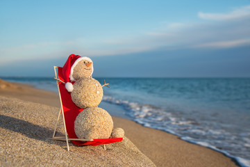 Sandy snowman sunbathing in beach lounge. Holiday concept for Ne