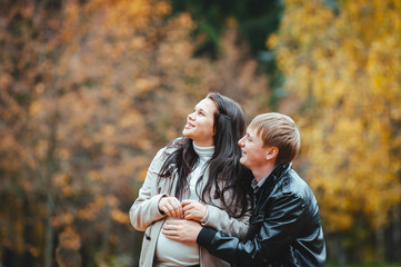 young married pregnant couple walking in the autumn park
