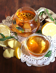 Kettle and cup of tea with ginger on napkin on wooden table