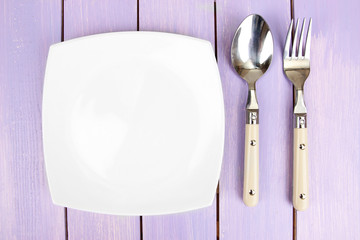 Plate and cutlery on wooden table close-up
