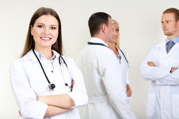 Fototapeta premium Doctor standing in front of coworkers on grey background