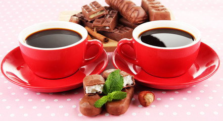 Red cups of strong coffee and chocolate bars close up