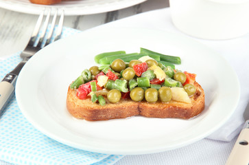 Sandwich with vegetables and greens on plate close-up