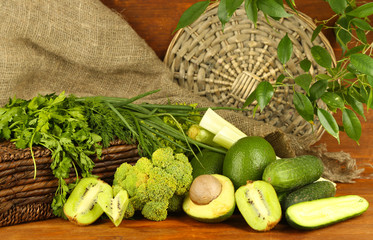 Fresh green vegetables and fruits, on wooden background