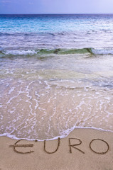 Euro word written in the sand on a beach, washed away by sea