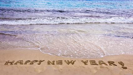 Happy new year and exclamation point written in the sand