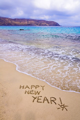 Happy new year and exclamation point written in the sand