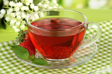 Delicious strawberry tea on table on bright background