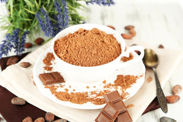 Cocoa powder in cup on napkin on wooden table