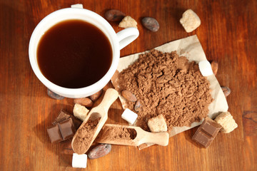 Cocoa in cup and coca powder on wooden table