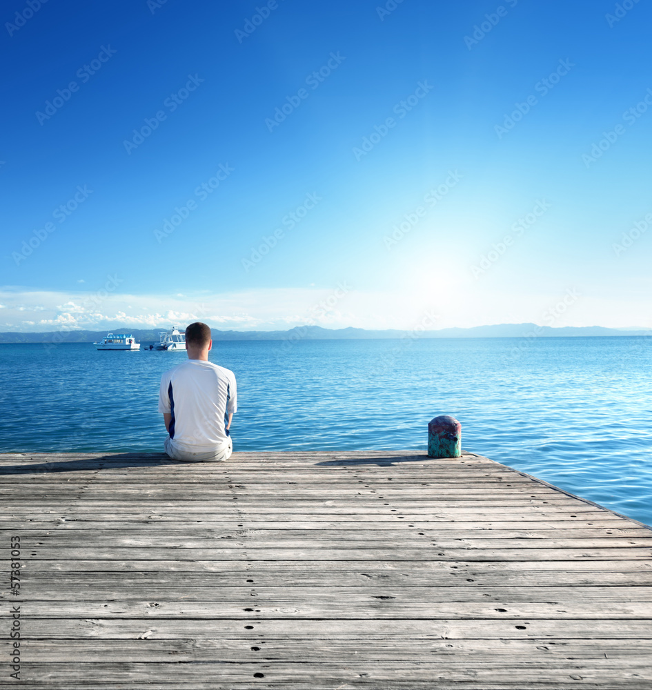 Wall mural young man relax siting on pier - Wall murals