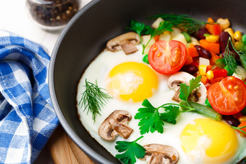 Fried eggs in a pan with vegetables