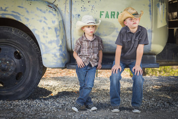 Two Young Boys Wearing Cowboy Hats Leaning Against Antique Truck