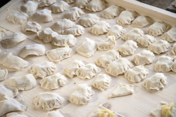 Fototapeta na wymiar Raw dumplings with potato on carving board.