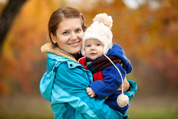 Portrait of young woman and her baby son in autumn park