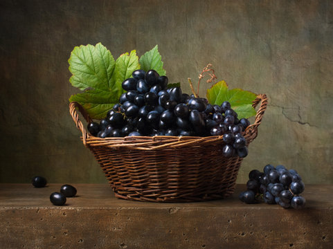 Still life with black grapes in a basket on the table