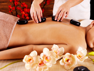woman's body with  hot stones on back  in spa salon