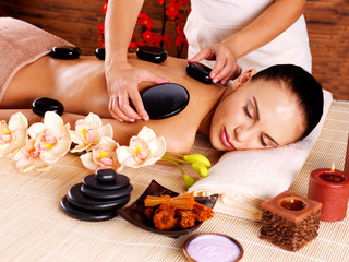 Obraz na płótnie Canvas Adult woman having hot stone massage in spa salon