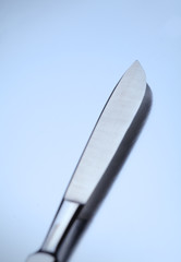 Sharp surgical scalpel on a metal background.