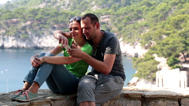 Couple on trip taking photo with cellphone in beautiful scenery