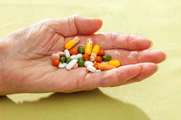 Assorted tablets in the hand of an old woman.