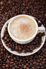 Cup of cappuccino  with coffee beans around
