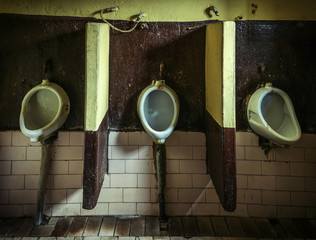 Three dirty urinals in public gents