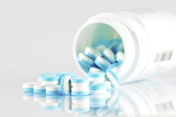 A half of blue and white pills over white background