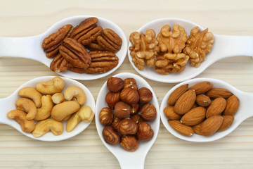 Selection of nuts on white porcelain spoons