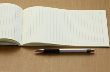 Pen and business plan notebook on wooden desk